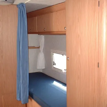 Letto singolo allestito nella zona laterale del camper, con armadio e gavone portasci esterno.