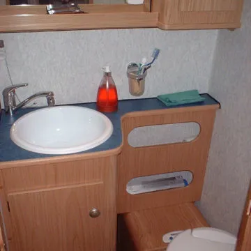 Bagno con blocco sottolavello e portaoggetti in legno, specchio e pensile in coordinato.