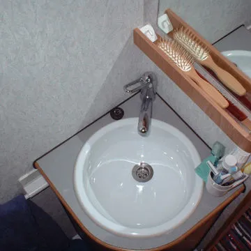 Bagno per camper e caravan con mensolina in legno portaoggetti e specchio.