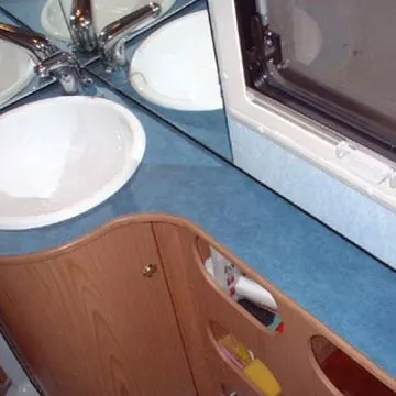 Mobile lavandino con portaoggetti sottopiano in legno, con piano arrotondato in laminato blu.